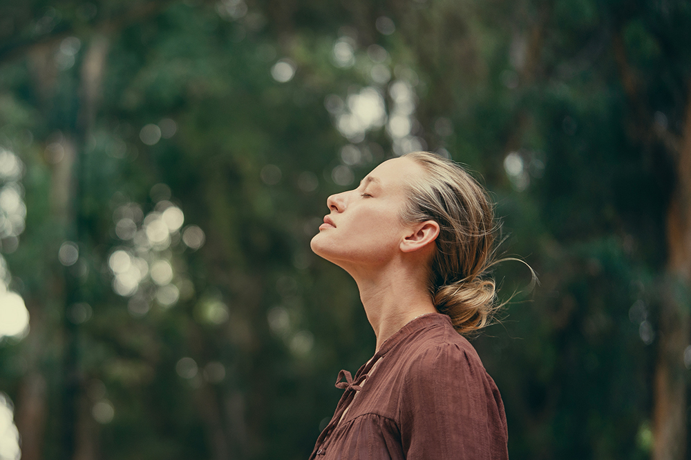 Frau in grüner Natur die durchatmet